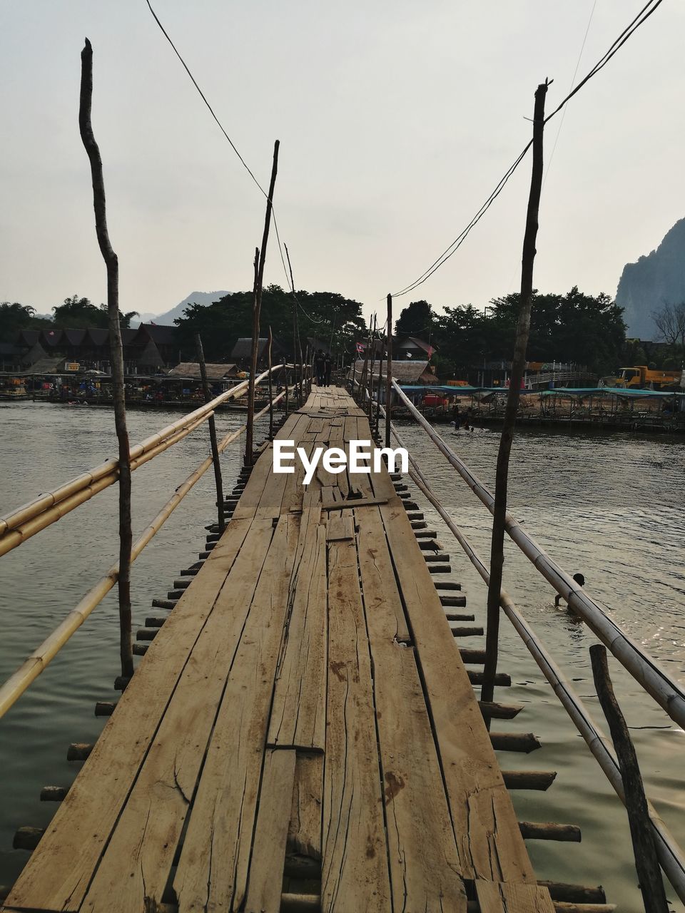 Boats moored on jetty by river against sky