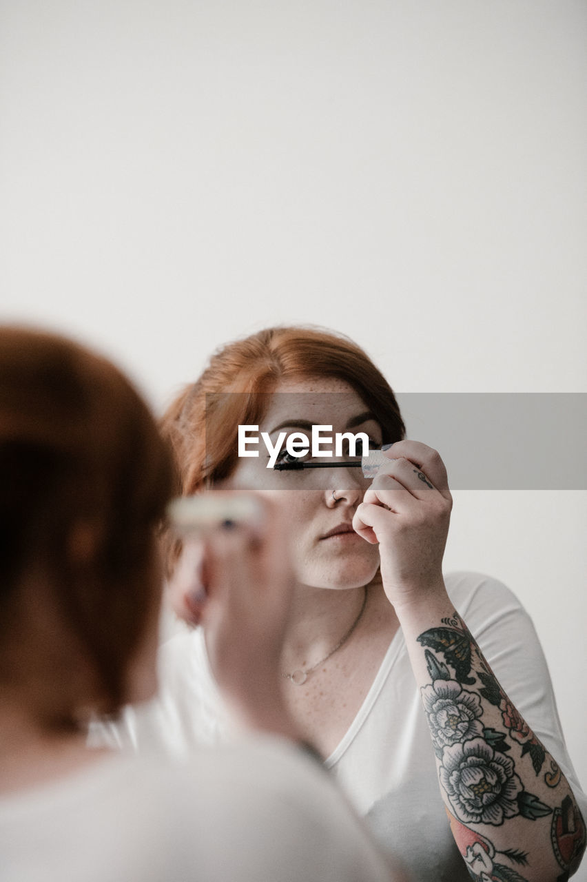 Young woman applying make-up at home