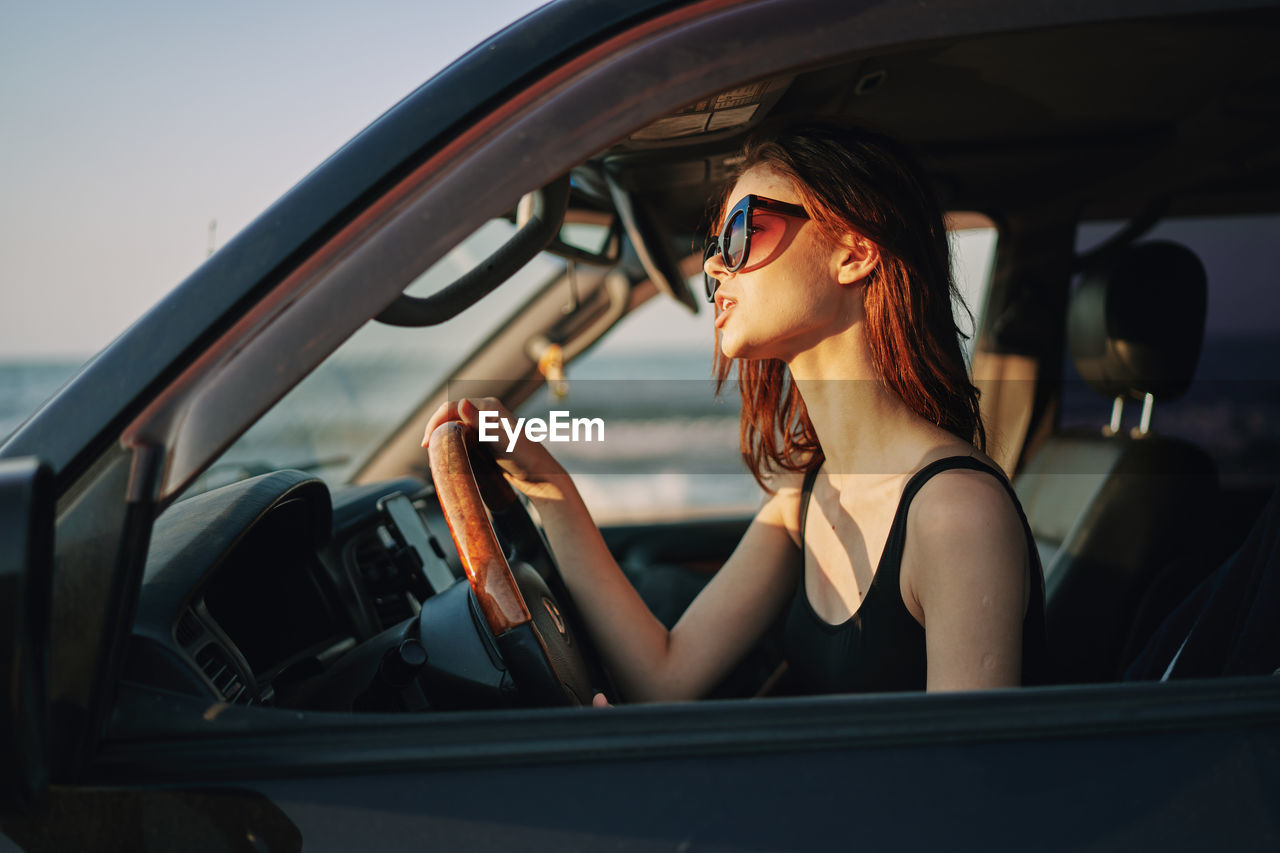 portrait of woman wearing sunglasses in car
