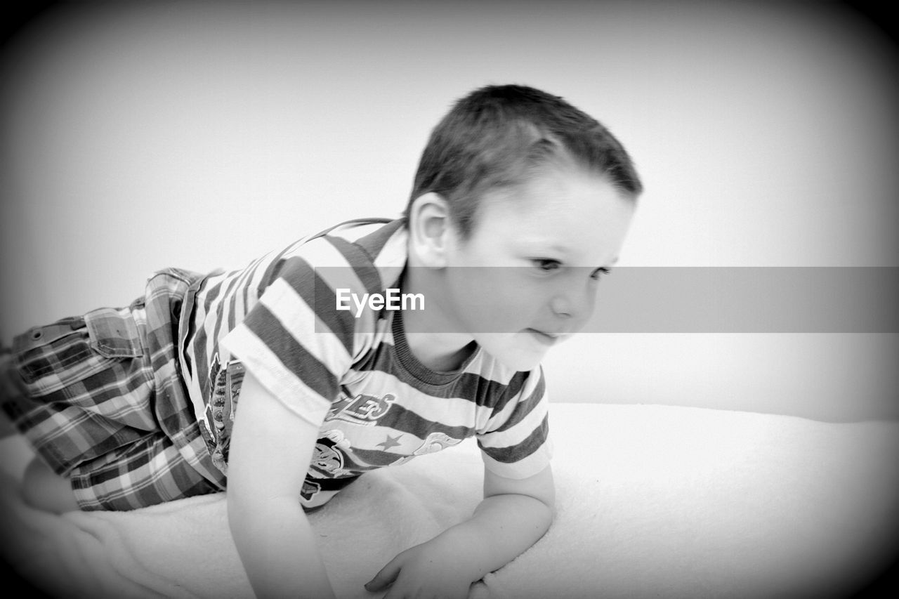 Cute boy reclining on bed at home