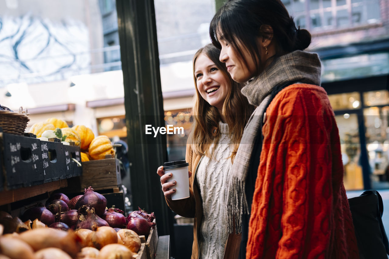 Happy sisters buying vegetables at market stall