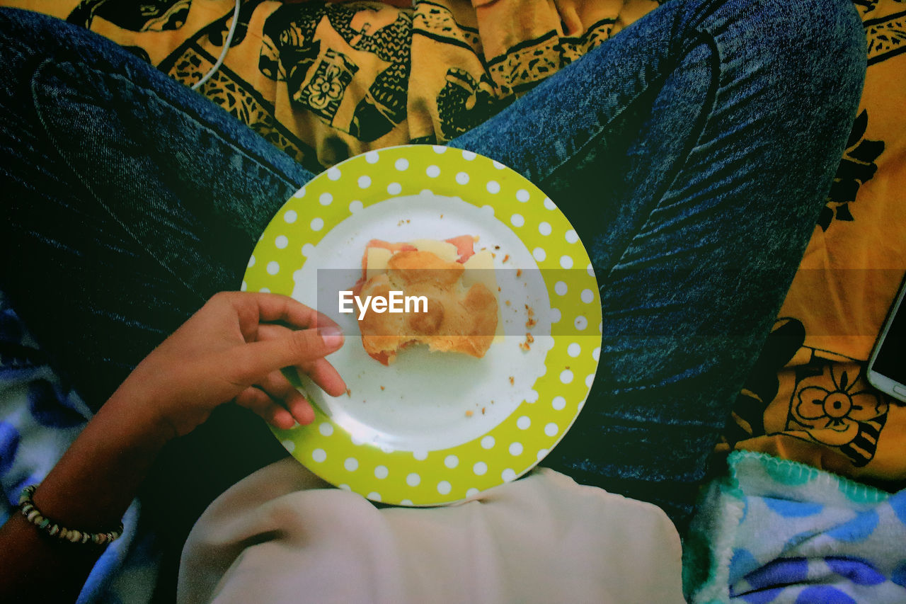 Low section view of woman holding cookie in plate 