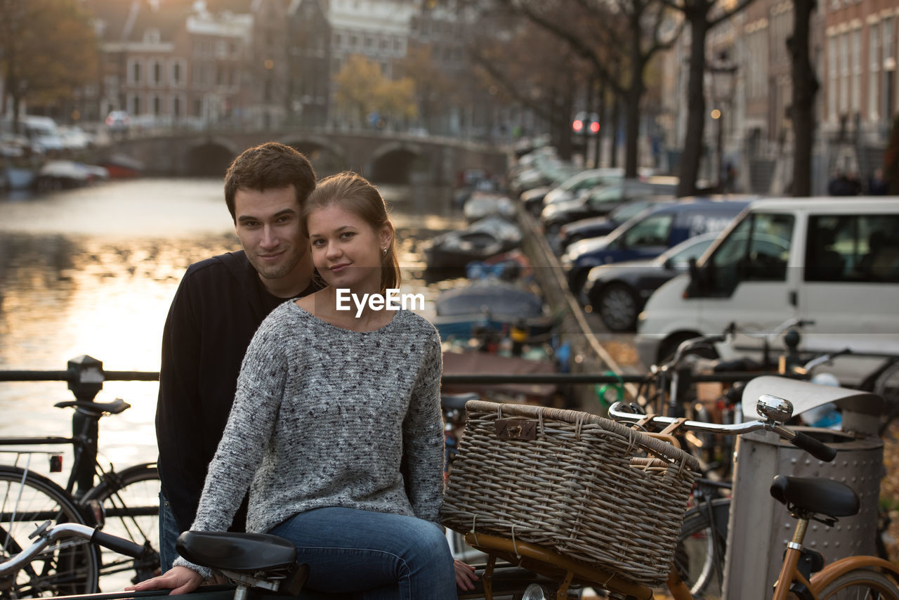 Portrait of smiling friends by bicycle in city