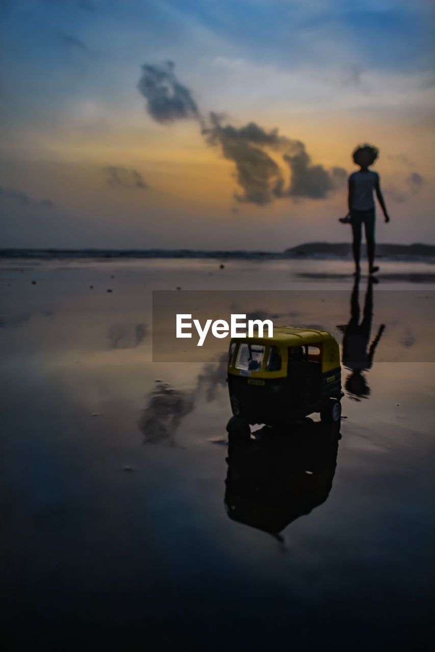 Toy on beach against sky during sunset