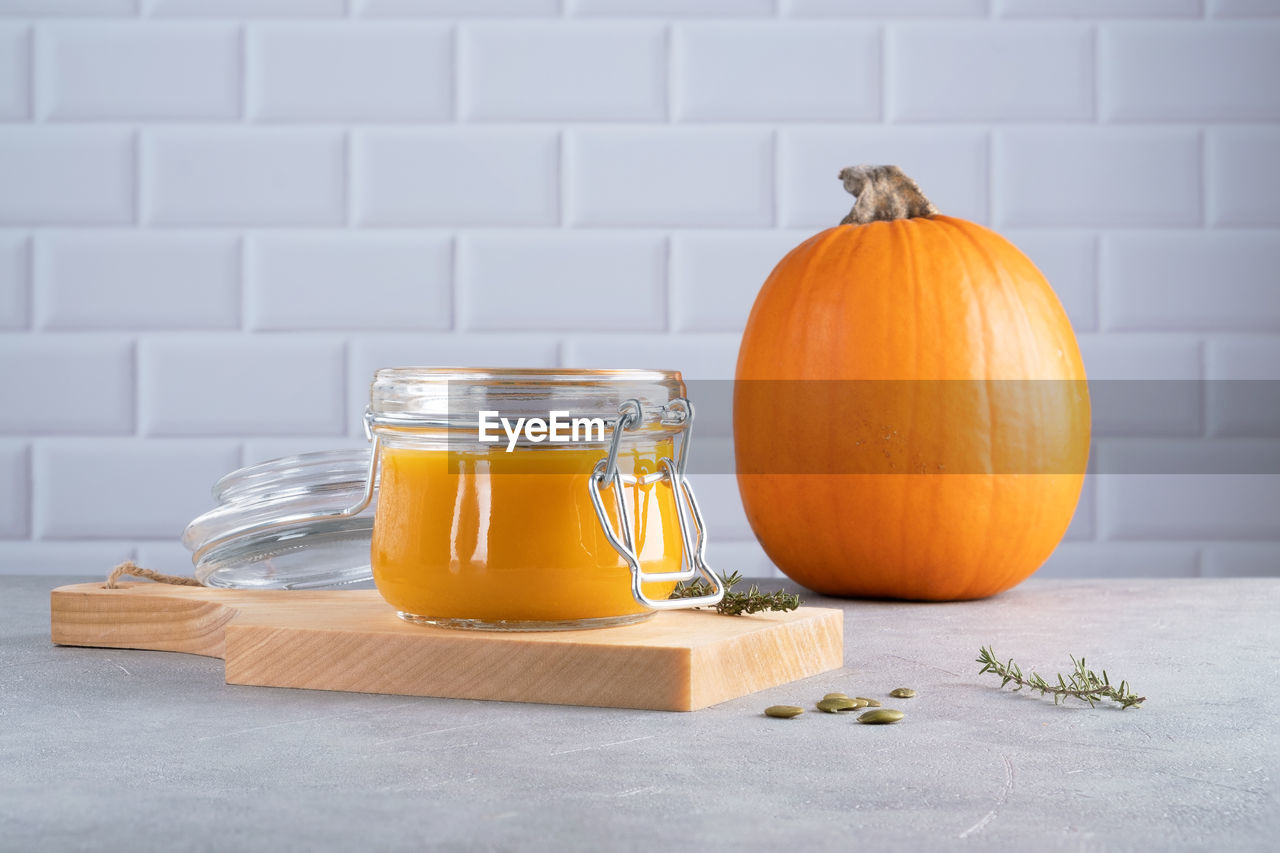 Pumpkin puree soup with pumpkin seeds and thyme in a glass jar on wooden kitchen board. ripe pumpkin