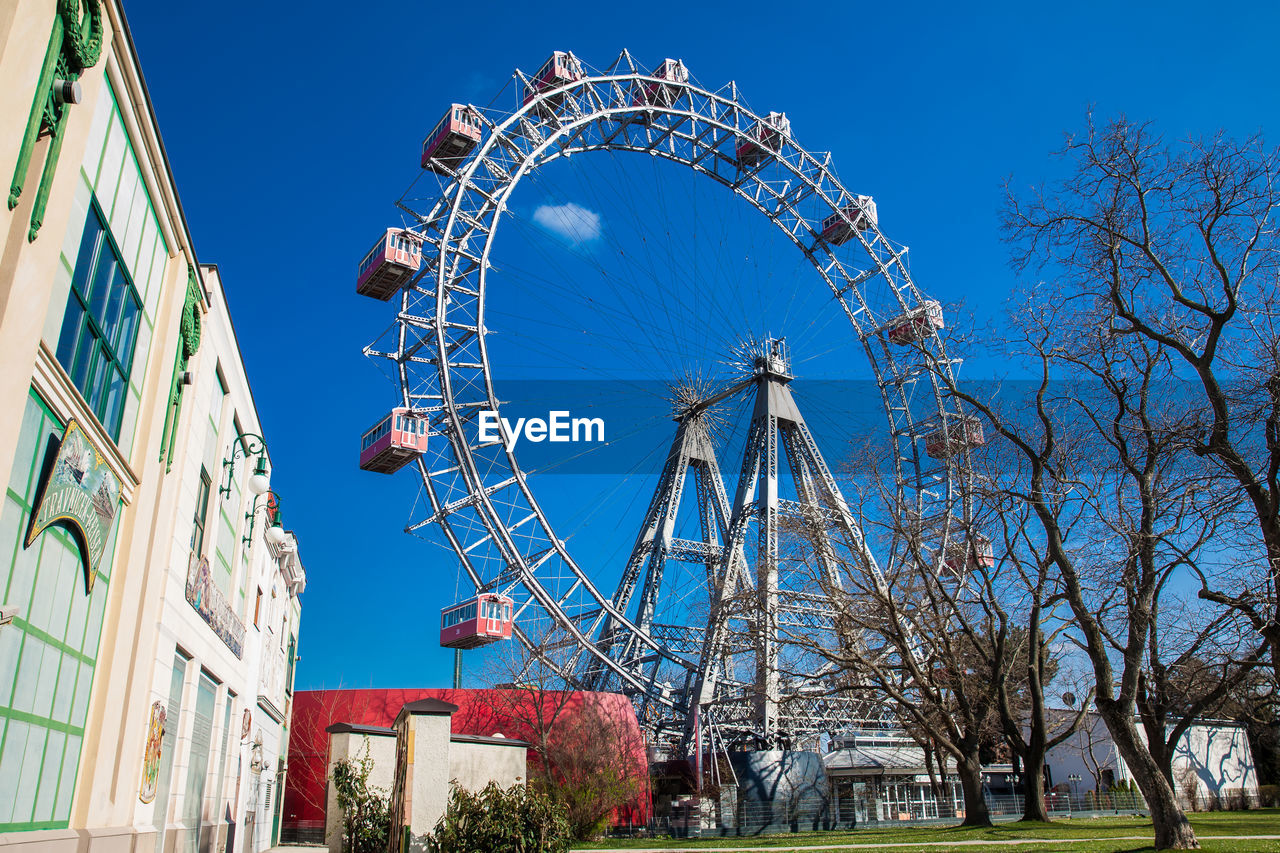 Low angle view of ferris wheel against buildings in city