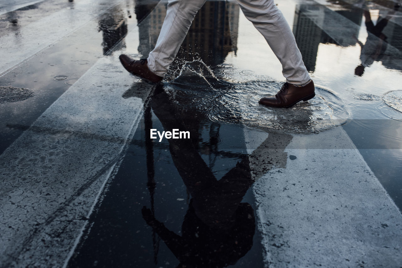 Low section of man walking on wet street