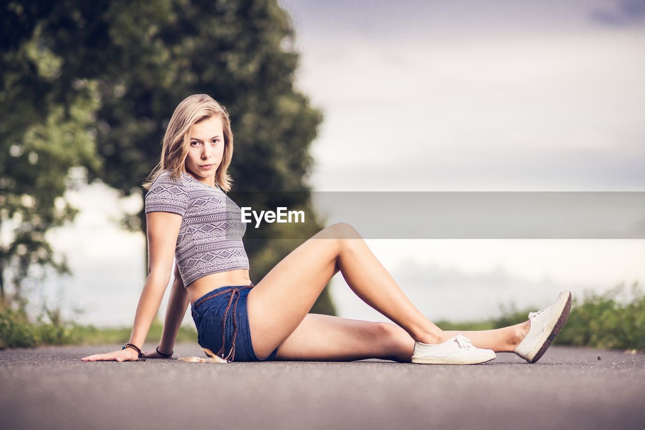 PORTRAIT OF BEAUTIFUL YOUNG WOMAN AGAINST TREE