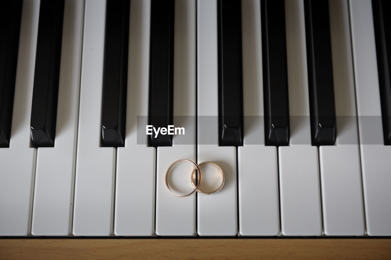 High angle view of wedding rings on piano keys