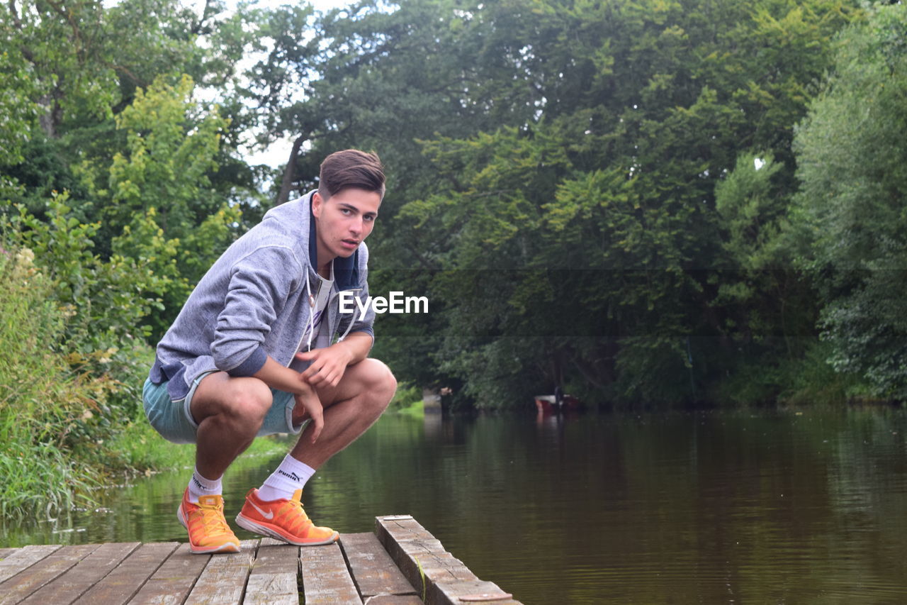 YOUNG MAN SITTING ON JETTY