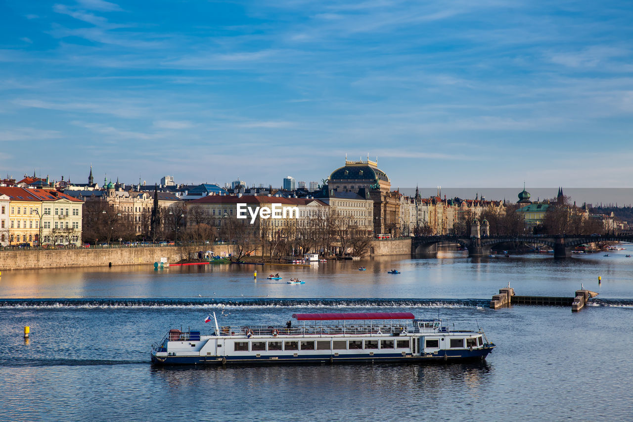 Boats in river against buildings in city