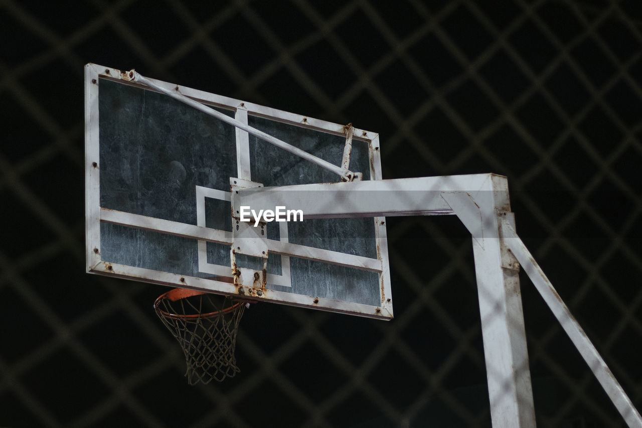 LOW ANGLE VIEW OF BASKETBALL HOOP IN FENCE