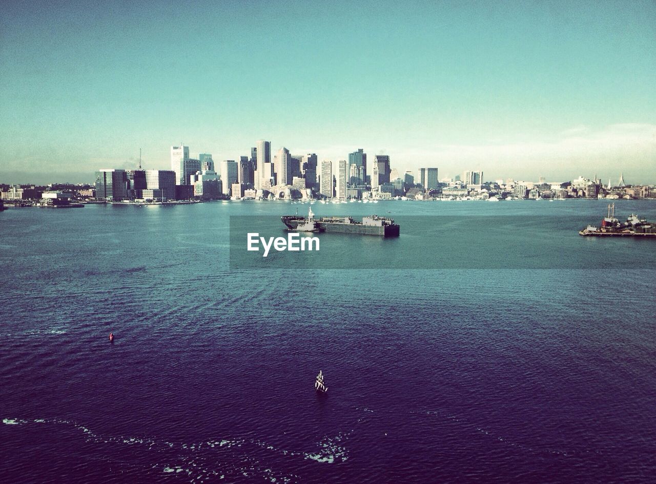 Ferries in sea with skyscrapers in background