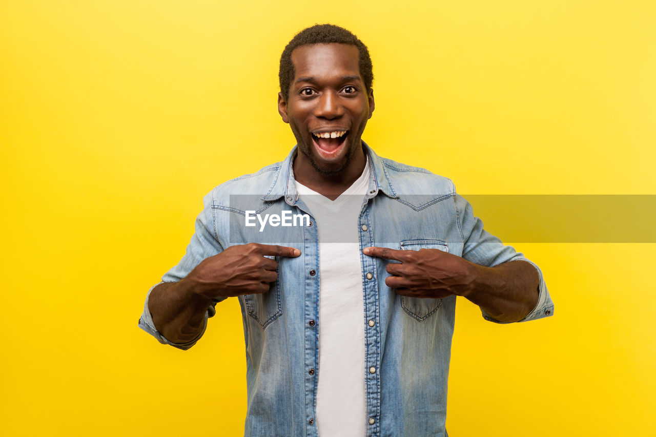 Portrait of smiling man standing against yellow background