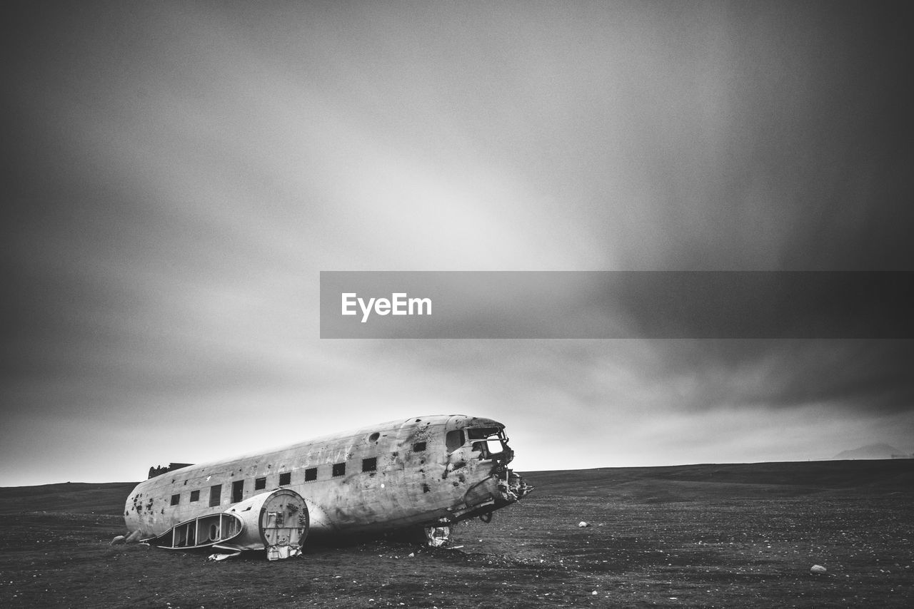 Abandoned airplane on beach against sky