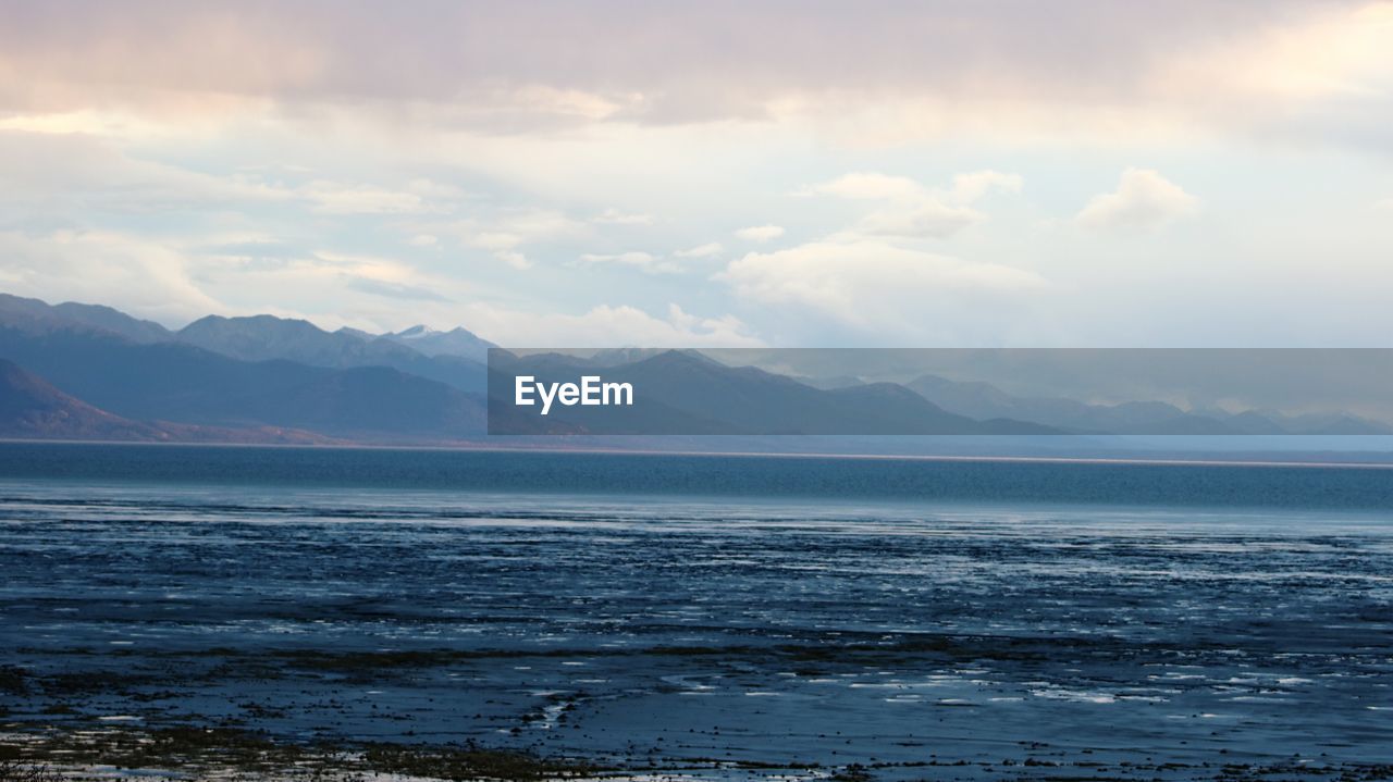 Scenic view of sea and mountains against sky