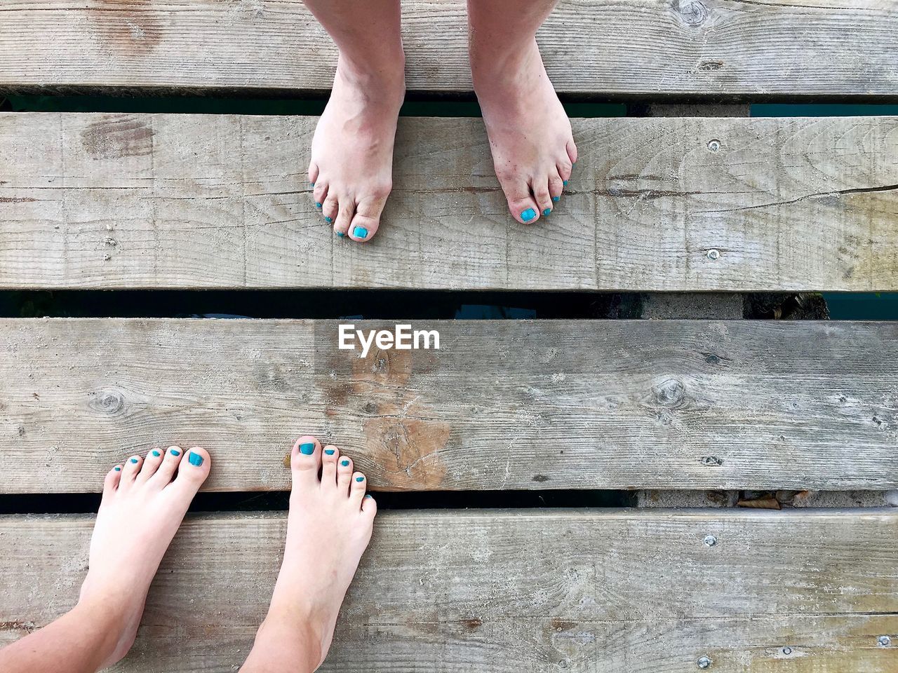 Low section of women with barefoot standing on wooden plank