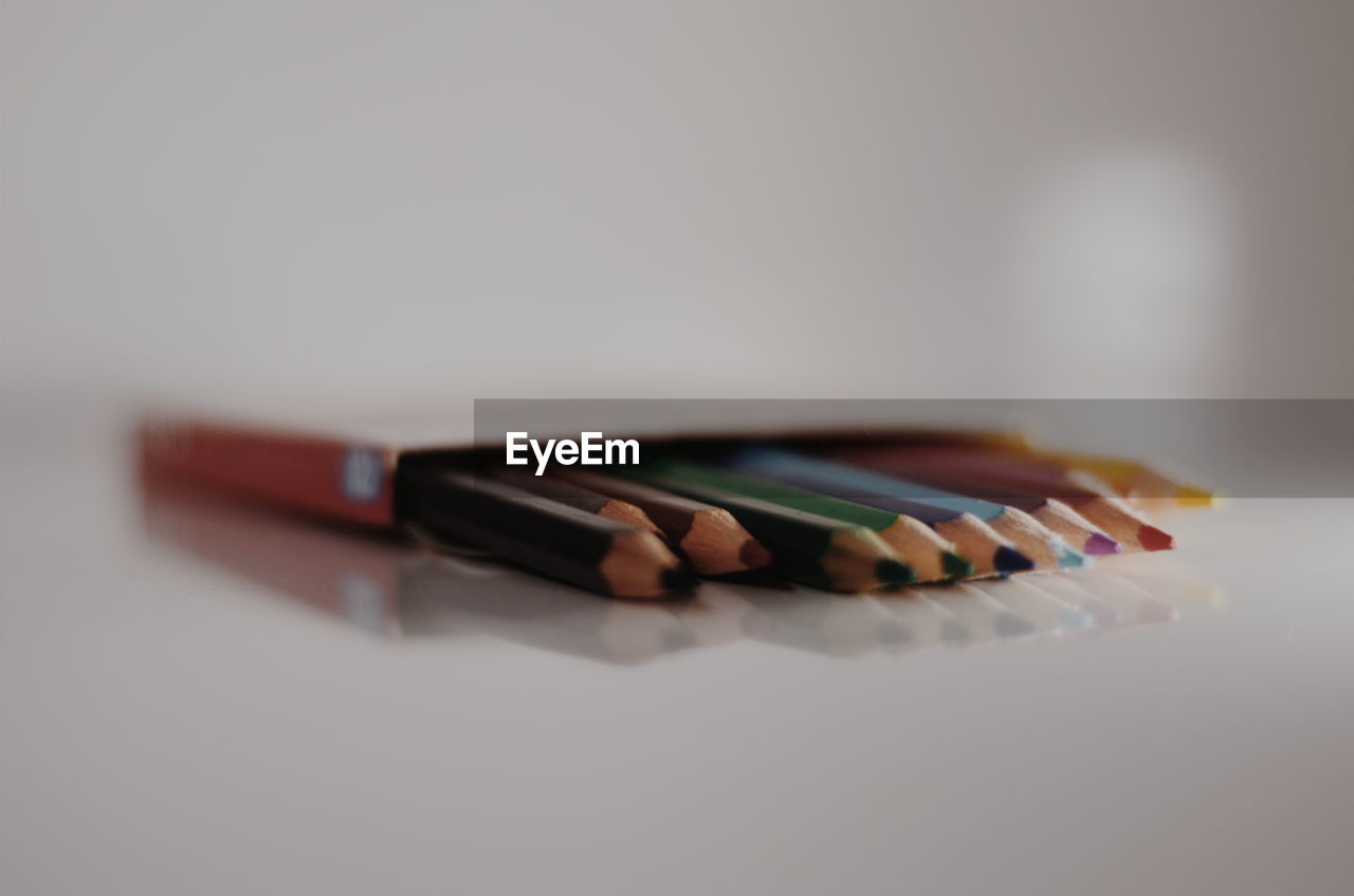 CLOSE-UP OF COLORED PENCILS ON WHITE TABLE