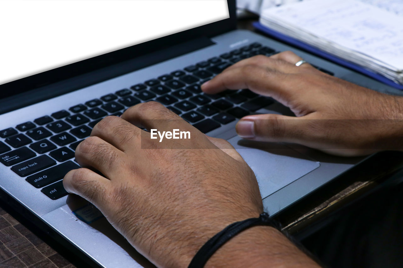 A closeup shot of male hands working with a laptop person