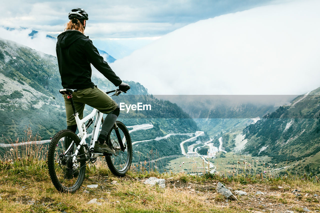 Rear view of man standing on mountain with bike
