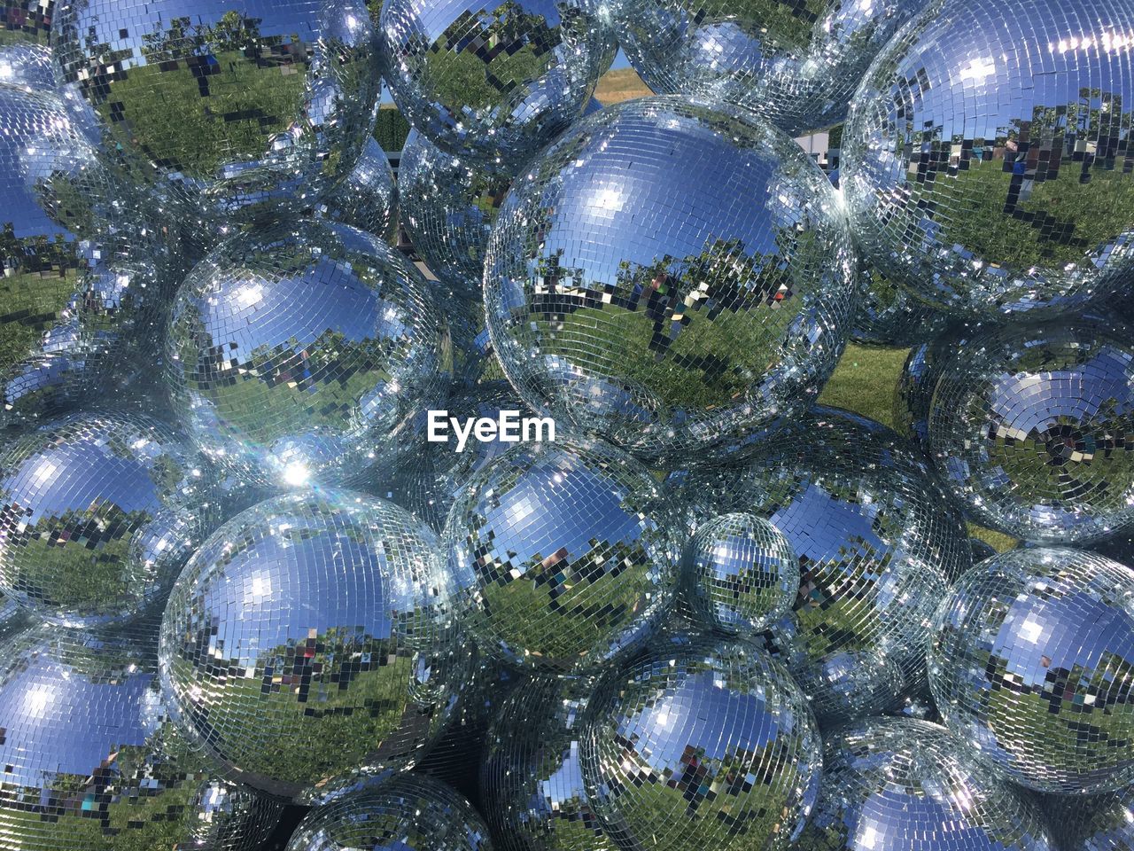 Full frame shot of reflection on shiny disco balls during sunny day