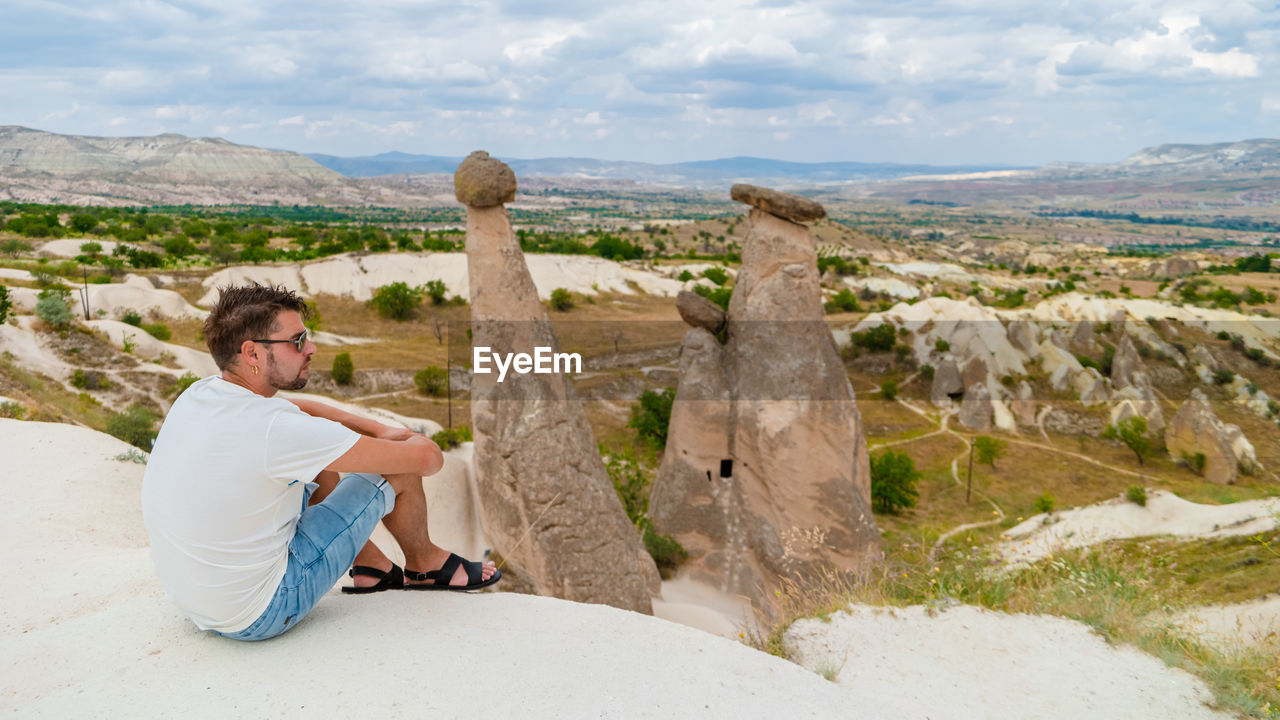 rear view of woman standing on rock against sky