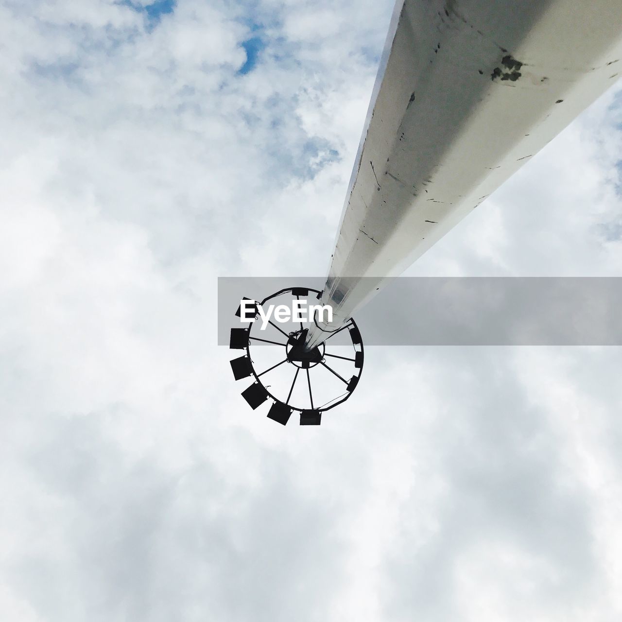 LOW ANGLE VIEW OF AIRPLANE AGAINST CLOUDY SKY