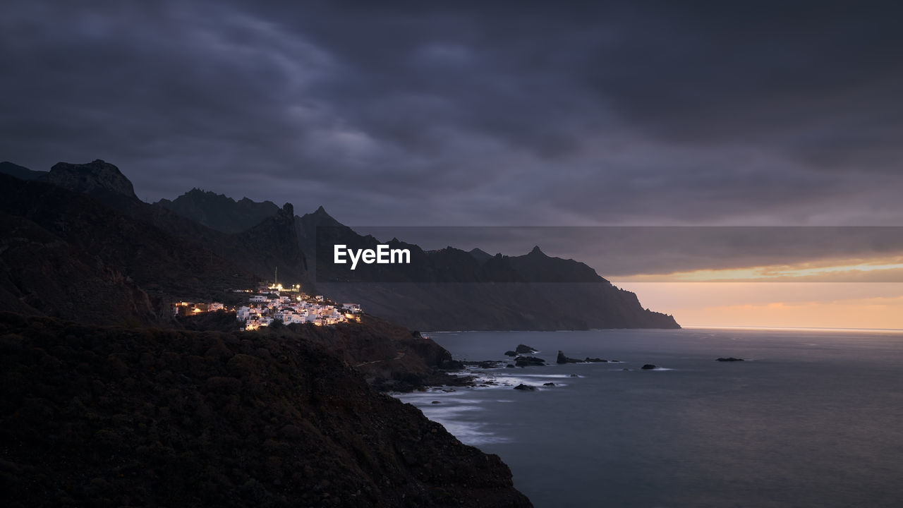 Cliffs in north coastline of tenerife at moody sunset. village in anaga mountains, tenerife.