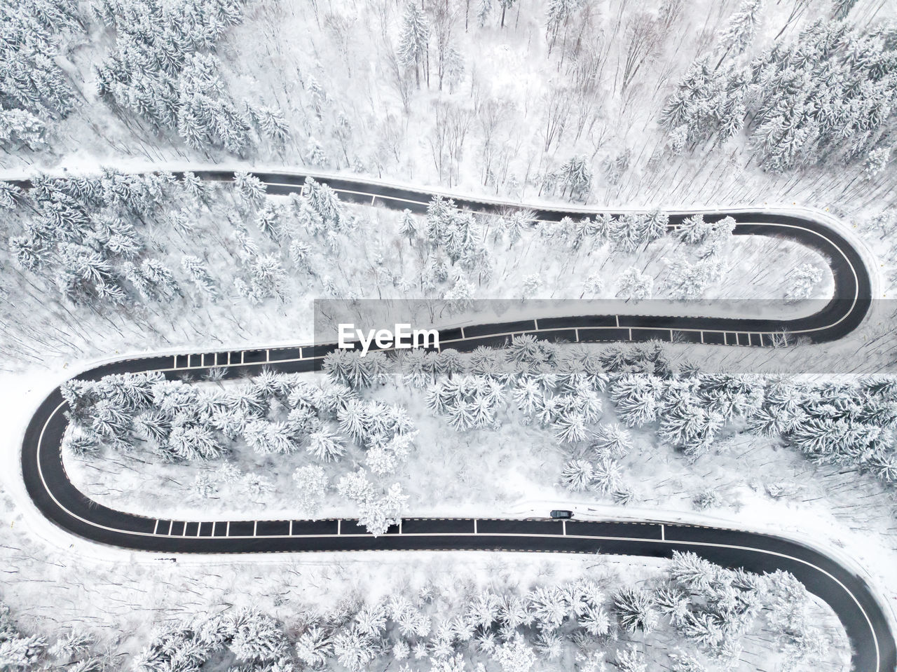 Winding road through the forest, from high mountain pass, in winter time. aerial view by drone