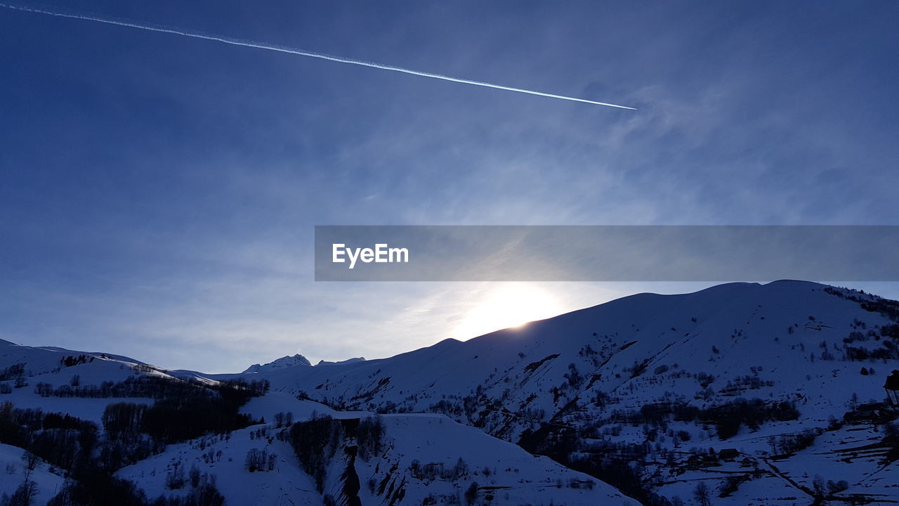 SCENIC VIEW OF VAPOR TRAIL IN SNOW AGAINST BLUE SKY
