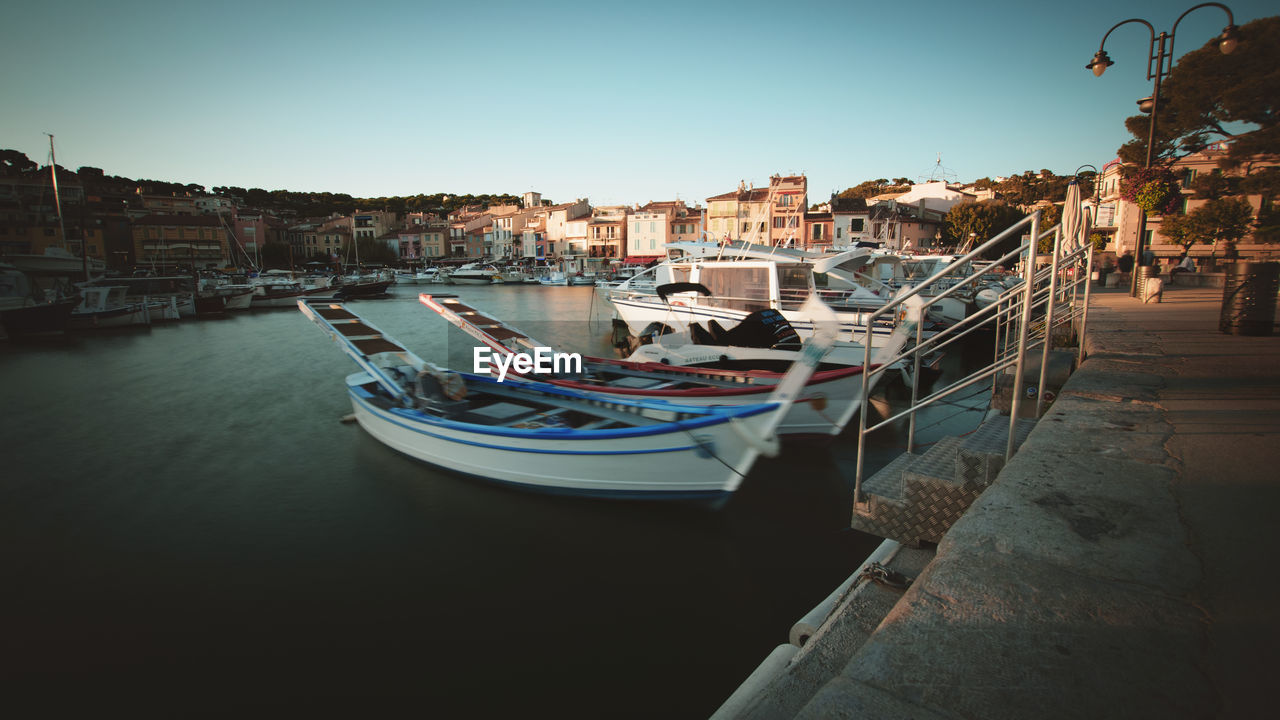 Boats moored at harbor against clear sky