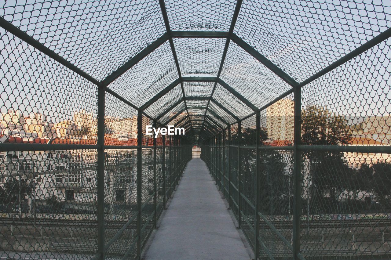 Bridge against sky seen through chainlink fence