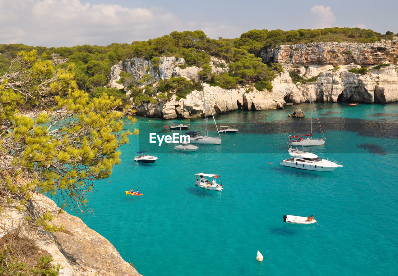 Boats in sea against rock formations