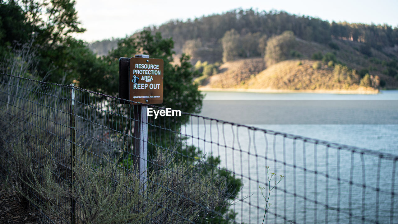 Information sign by lake against trees