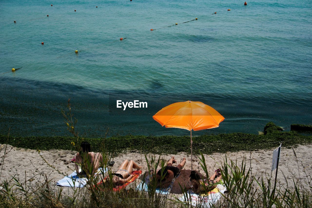 People and orange parasol at beach