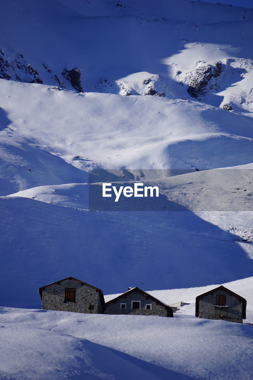 Scenic view of snow covered landscape and houses against sky