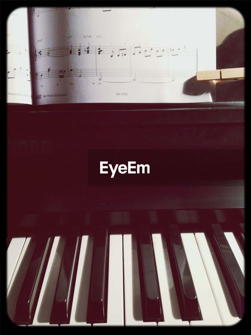 Close-up of piano keys with music sheets