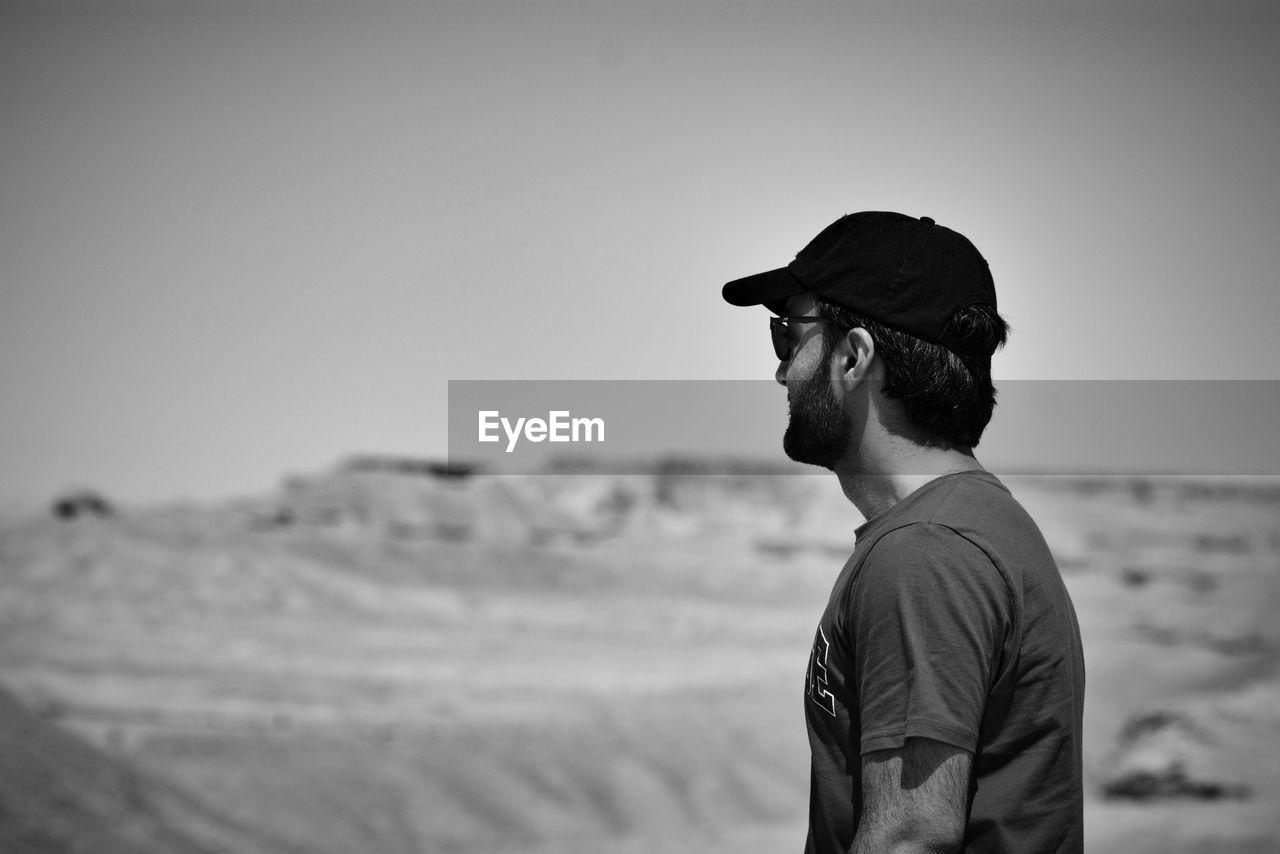 Side view of man looking away against clear sky