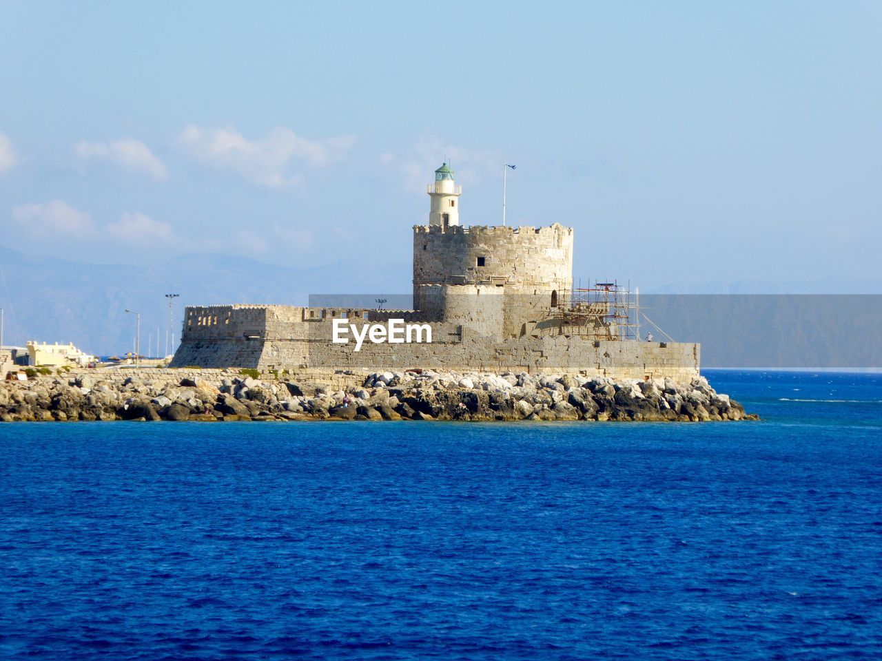 Scenic view of castle surrounded by calm blue sea against sky