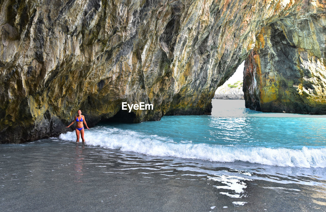 Mid adult woman in bikini standing at beach