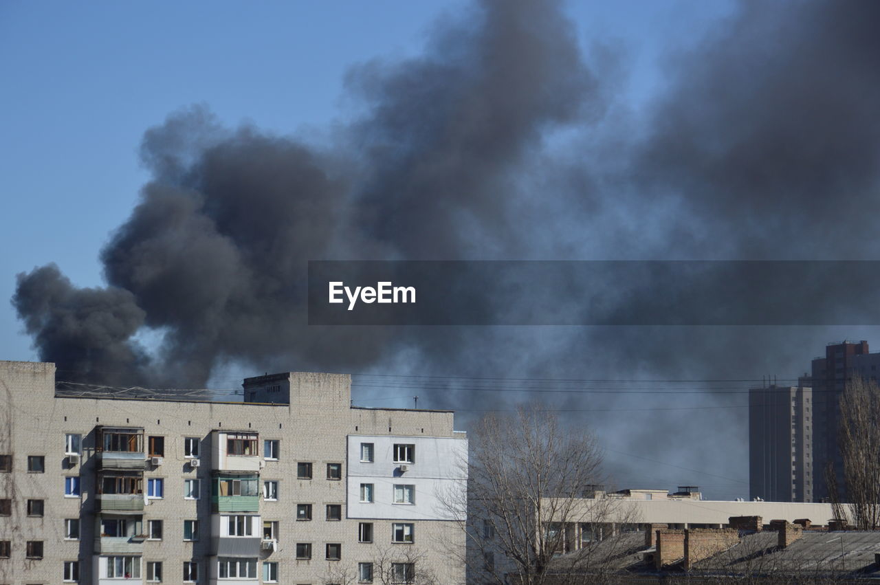 There is black smoke from a rocket or bomb explosion in a city during a war