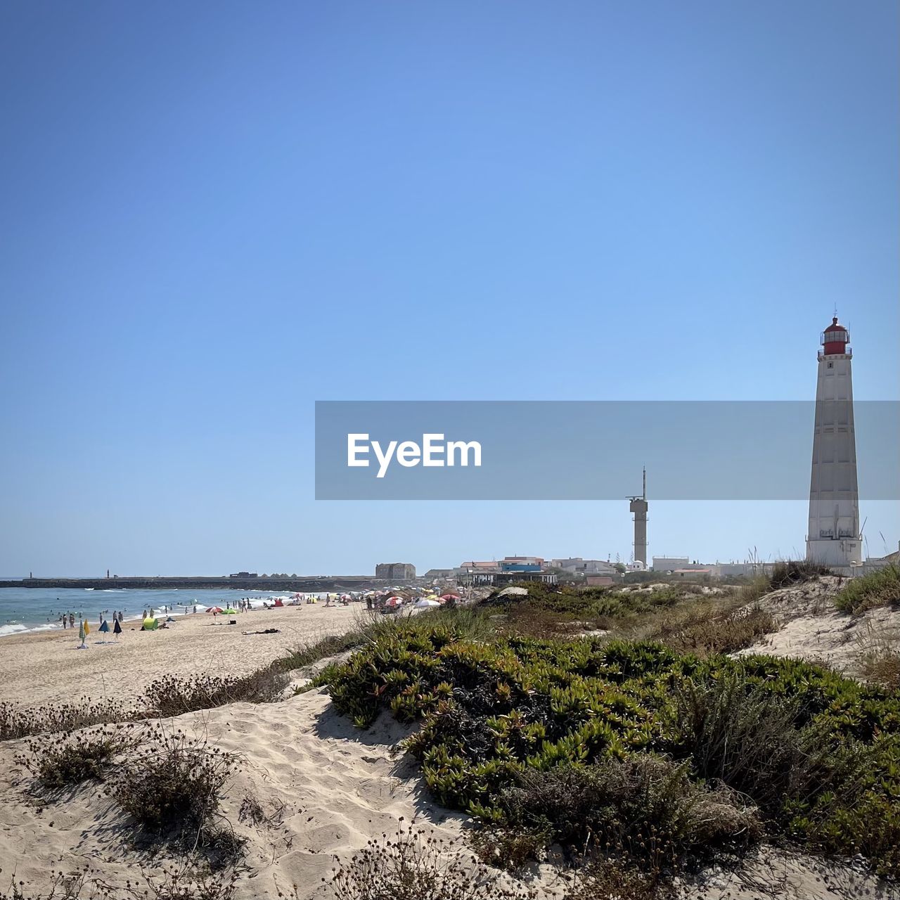 lighthouse, sky, sea, beach, tower, architecture, land, water, coast, guidance, built structure, building exterior, nature, clear sky, building, travel destinations, ocean, blue, security, travel, protection, shore, coastline, scenics - nature, sand, no people, tourism, day, copy space, horizon, environment, outdoors, sunny, landscape, beauty in nature, horizon over water, sunlight, tranquility, summer, water's edge, plant, trip, non-urban scene, holiday, history, vacation