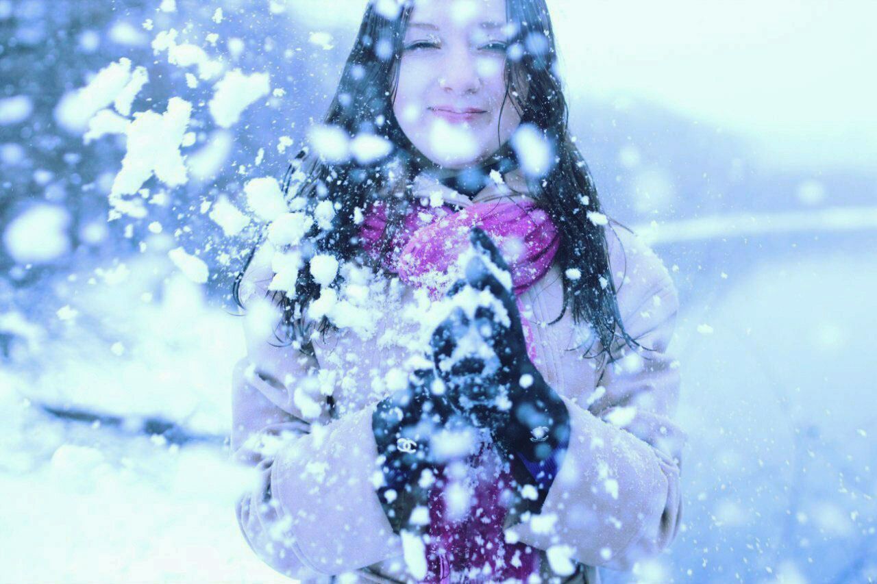 Happy woman holding snowflakes while snowing