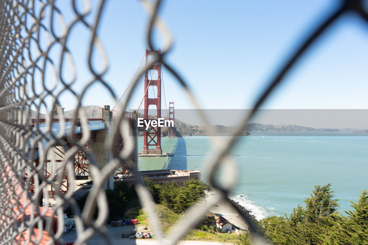 View of chainlink fence against clear sky and golden gate bridge