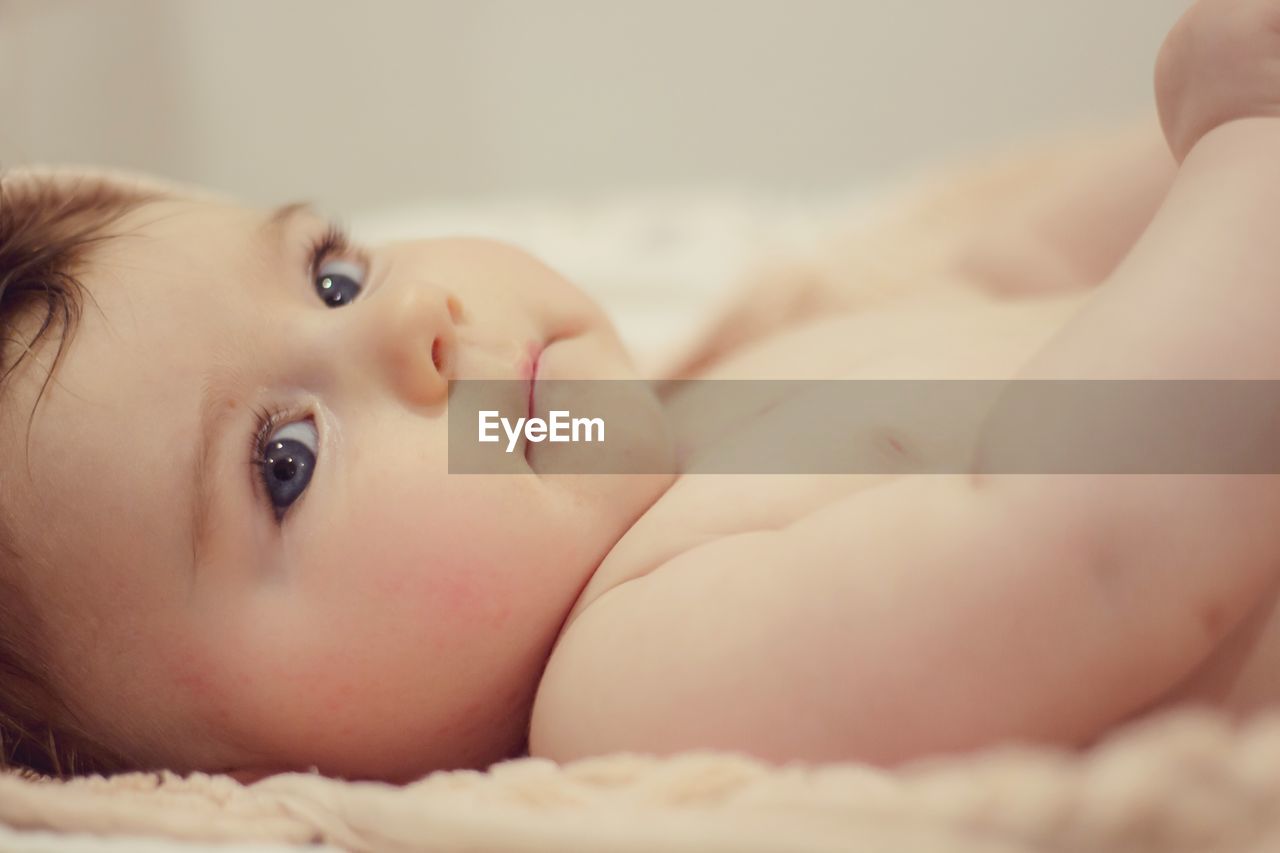 Cute baby looking away while lying on bed