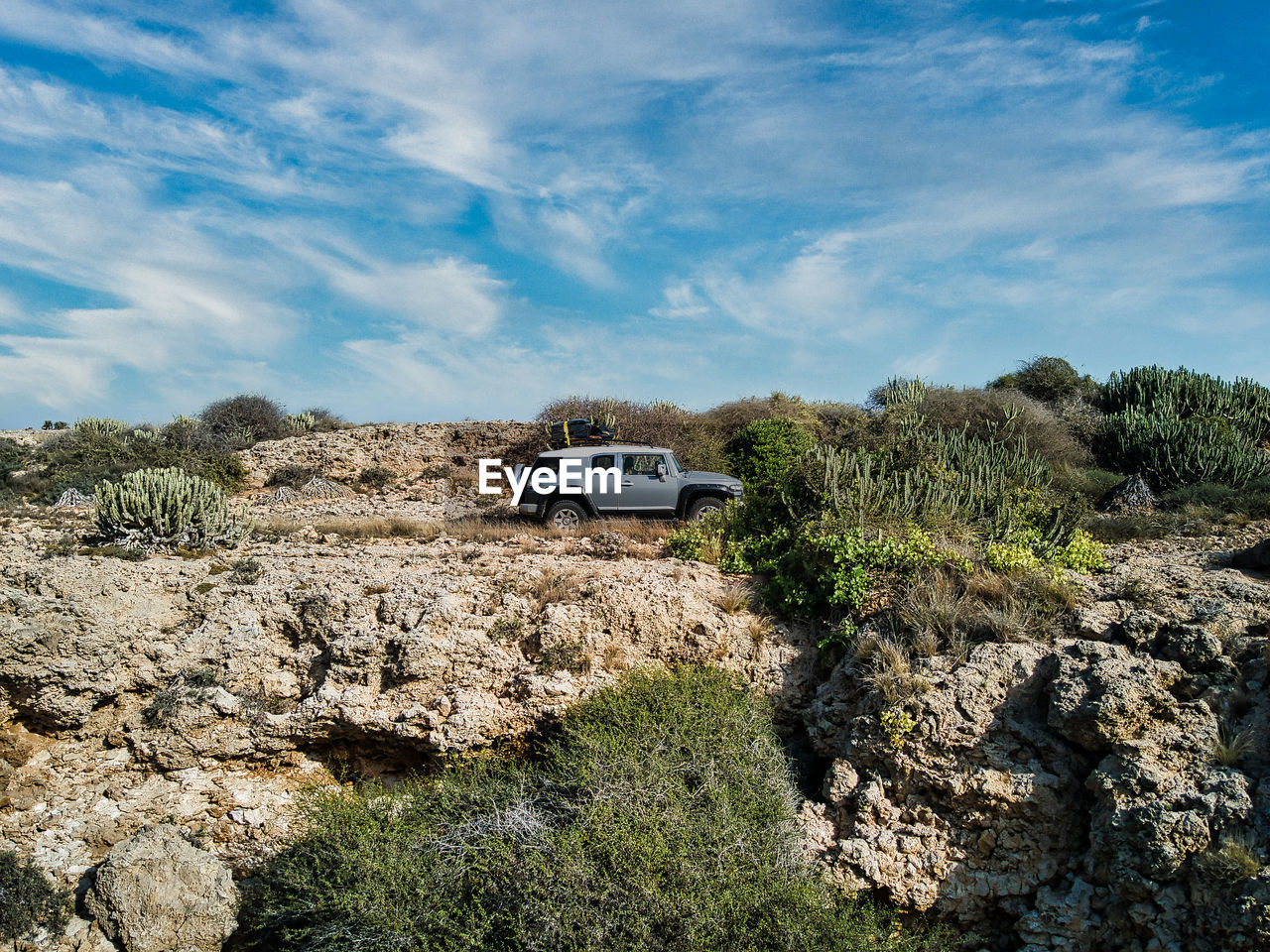 mode of transportation, transportation, motor vehicle, car, sky, nature, cloud, landscape, rock, travel, environment, wilderness, land vehicle, land, 4x4, plant, scenics - nature, blue, non-urban scene, terrain, vehicle, no people, off-roading, road, journey, adventure, coast, tree, sea, mountain, off-road vehicle, day, outdoors, travel destinations, beauty in nature, extreme terrain, tourism, road trip, geology, natural environment, remote, sunlight, desert, soil, outdoor pursuit, vacation