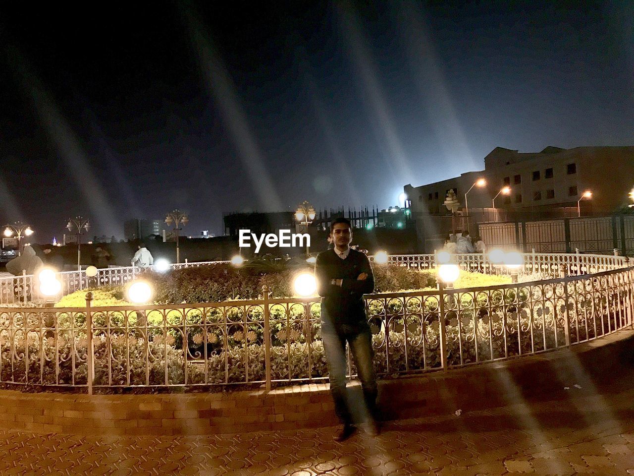 CROWD STANDING ON ILLUMINATED BRIDGE AT NIGHT