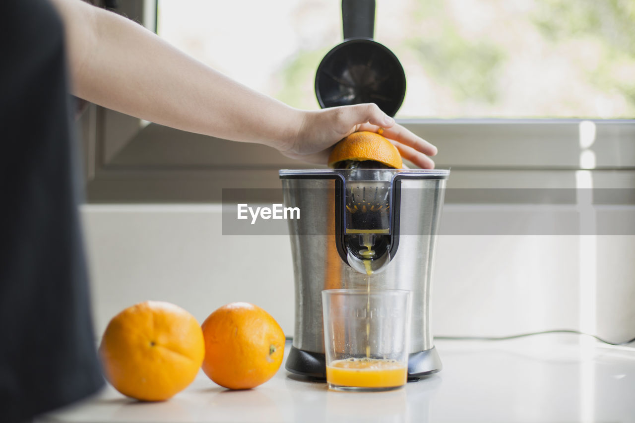 Close-up of hand holding orange juice on table