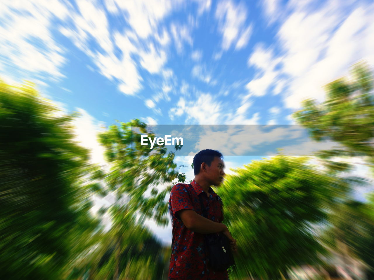 Blurred motion of young man standing against trees