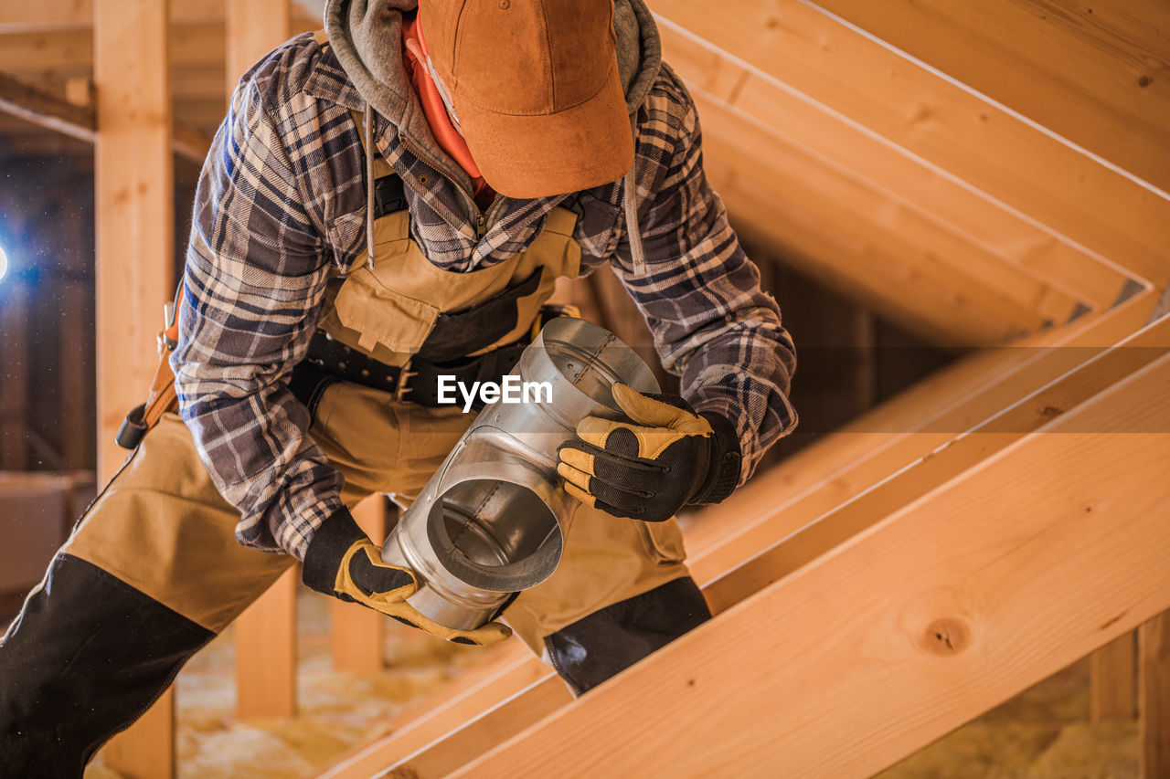 MIDSECTION OF MAN WORKING ON WOOD WITH PIANO